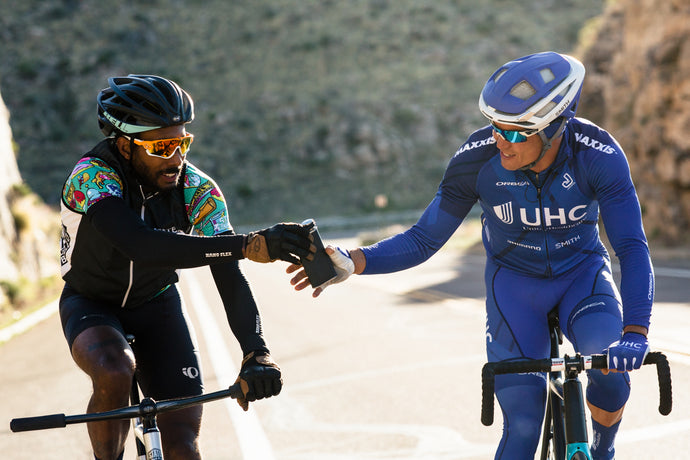 One rider passing another a water bottle